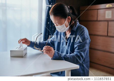 A senior woman in her 60s has itchy eyes and grabs a tissue. A senior woman in her 60s has itchy eyes and grabs a tissue. 111657851