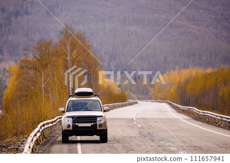 SUV on scenic autumn road in the forest SUV on scenic autumn road in the forest 111657941