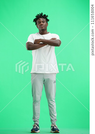 A man, full-length, on a green background, crossed his arms 111658004