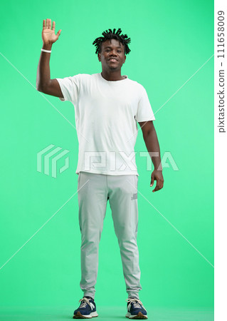 A man, full-length, on a green background, waving his hand A man, full-length, on a green background, waving his hand 111658009
