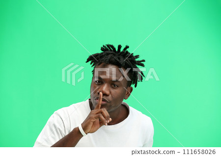 A man, close-up, on a green background, shows a sign of silence 111658026