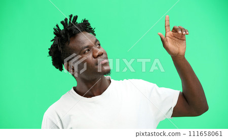 Man, close-up, on a green background, pointing up 111658061