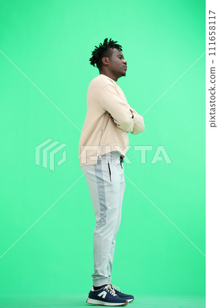 A man, full-length, on a green background, crossed his arms 111658117