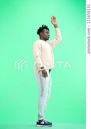 A man, full-length, on a green background, waving his hand A man, full-length, on a green background, waving his hand 111658131