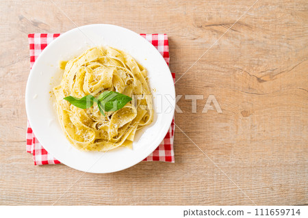 pesto fettuccine pasta with parmesan cheese on top pesto fettuccine pasta with parmesan cheese on top 111659714