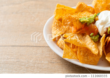 nachos tortilla chips with jalapeno, guacamole, tomatoes salsa and dip nachos tortilla chips with jalapeno, guacamole, tomatoes salsa and dip 111660335