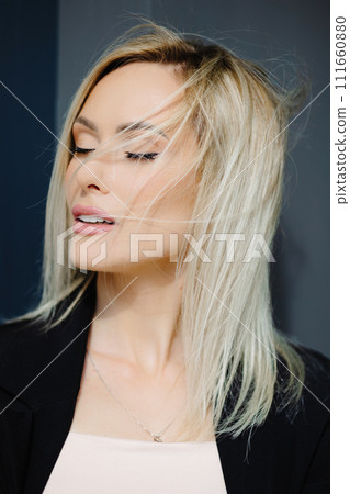 Portrait of blonde beautiful young stylish woman with fluttering hair on the gray wall in the city Portrait of blonde beautiful young stylish woman with fluttering hair on the gray wall in the city 111660880