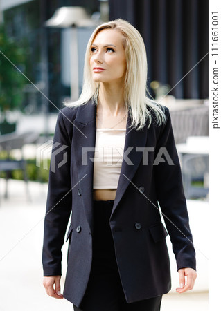 Business women style. Woman going to work walking on the street. Portrait of beautiful smiling female in stylish office clothes going on the street. 111661001
