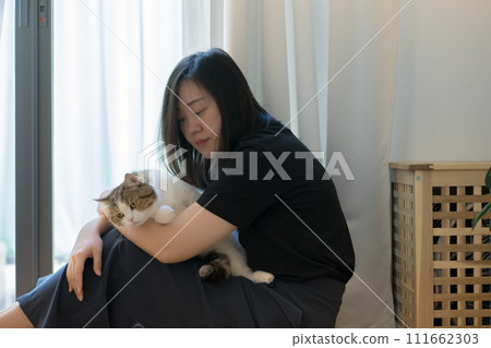 wellness and wellbeing concept with asian woman sit and play with her cat in livingroom wellness and wellbeing concept with asian woman sit and play with her cat in livingroom 111662303