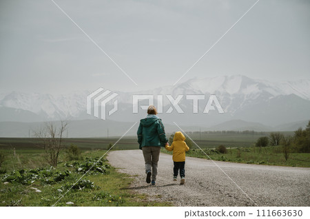 woman grandmother and her grandson travel along a road with a view of the mountains woman grandmother and her grandson travel along a road with a view of the mountains 111663630