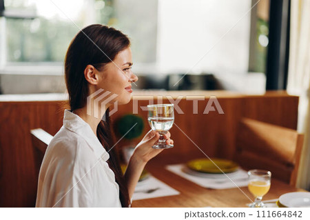 Happy woman enjoying a romantic dinner at home in a cozy dining room She is smiling ecstatically while sitting at a trendy dining table decorated with beautiful plates and a delicious homemade cake 111664842