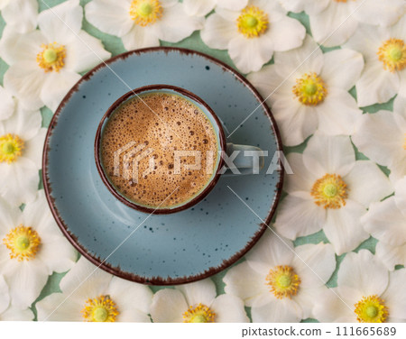 Morning blue cup of coffee and white anemone flowers on the table. Flat style. Morning blue cup of coffee and white anemone flowers on the table. Flat style. 111665689