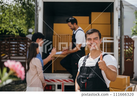 A smiling mover captured in a portrait unloads boxes into a new home from a truck. These removal company workers guarantee efficient moving and happiness. Moving day concept A smiling mover captured in a portrait unloads boxes into a new home from a truck. These removal company workers guarantee efficient moving and happiness. Moving day concept 111666320