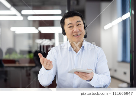 Smiling male customer service agent with headset in office environment, assisting clients with enthusiasm and professionalism. 111666947
