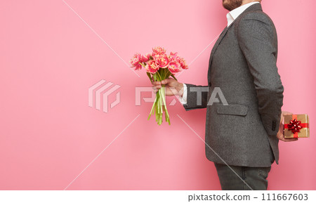 Man in suit with gift box and bouquet of tulips Man in suit with gift box and bouquet of tulips 111667603