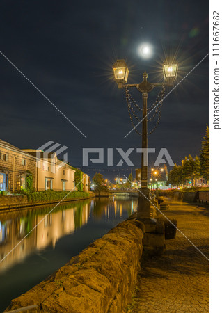 日本北海道小樽市小樽運河沿岸的煤氣燈和照明石倉庫照亮的夜景 111667682