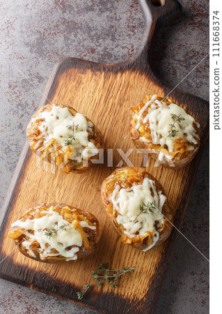 Twice baked potatoes stuffed with French onions and Gruyere cheese close-up in a bowl. Vertical top view 111668374