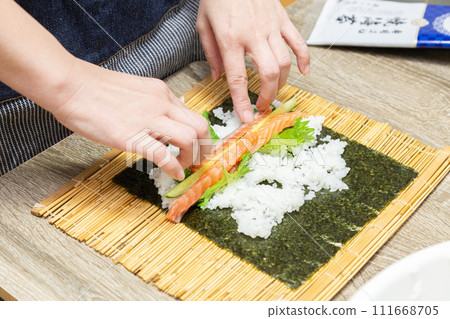 A housewife making sushi rolls by hand A housewife making sushi rolls by hand 111668705