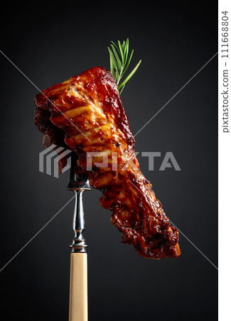 Grilled pork ribs with rosemary on a fork. Grilled pork ribs with rosemary on a fork. 111668804