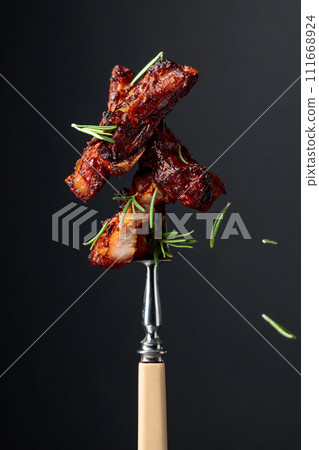 Grilled pork belly with rosemary on a fork. Grilled pork belly with rosemary on a fork. 111668924