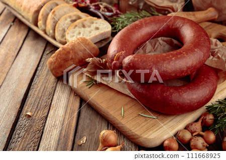 Smoked sausage with bread and spices on a old wooden table. 111668925