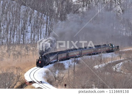 A steam locomotive traveling through the Kushiro Wetlands on a sunny winter day. Overhead view of the Temporary Pass railroad crossing. 111669138