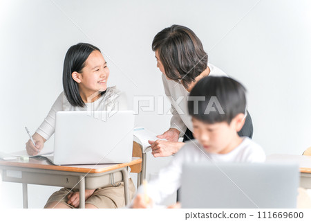 Elementary school girls and female instructors studying while using laptops in school classrooms (education, teacher, class, tutor) 111669600