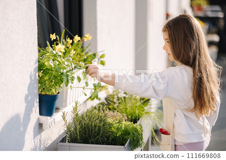 Four year old girl in bright overall stand by flowerpot and preparing to landing on balcony Four year old girl in bright overall stand by flowerpot and preparing to landing on balcony 111669808