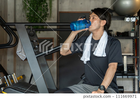 Young Asian man drinking water and protein during breaks and intervals at the fitness gym (hydration) 111669971