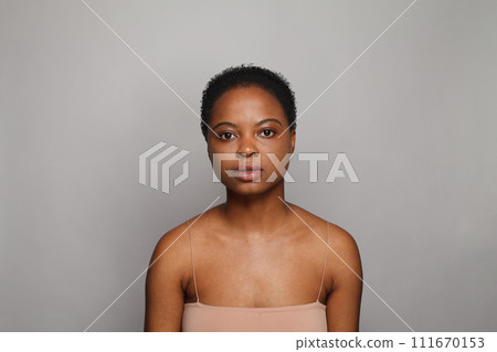Serious healthy young woman with dark shiny skin smiling looking at camera on white background.  111670153