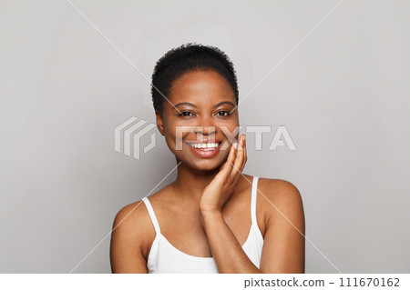 Attractive healthy young woman with dark shiny skin smiling looking at camera on white background.  111670162