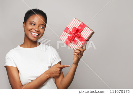 Young healthy woman holding colorful gift present box and pointing finger on white background. Young healthy woman holding colorful gift present box and pointing finger on white background. 111670175