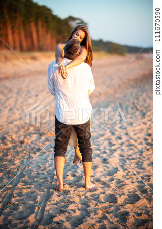Happy smiling young couple having fun in the sea on holidays. A man holding woman on hands. A man holding woman on hands 111670590