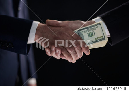 Handshake with the transfer of money on a black background Handshake with the transfer of money on a black background 111672046