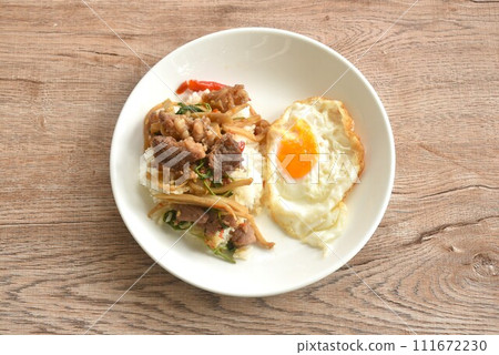 spicy stir fried bamboo shoot and slice beef meat with basil leaf topping egg on rice in plate   111672230