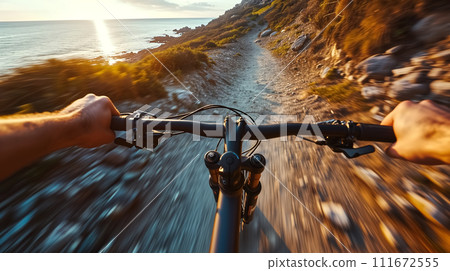 First-person view of a cyclist riding a mountain bike on a scenic coastal trail during sunset. 111672555
