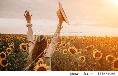 Woman in Sunflower Field: Happy girl in a straw hat posing in a vast field of sunflowers at sunset, enjoy taking picture outdoors for memories. Summer time. 111673066