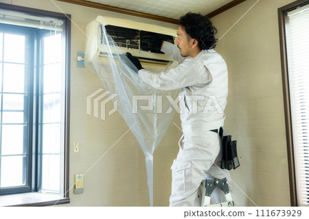 Male worker cleaning the air conditioner Male worker cleaning the air conditioner 111673929