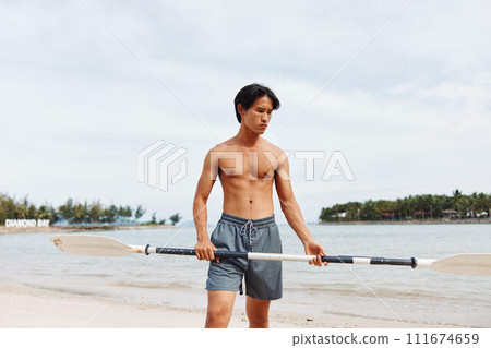 Active Asian Man Enjoying Sunset Paddleboarding Adventure on a Fun Beach Vacation Active Asian Man Enjoying Sunset Paddleboarding Adventure on a Fun Beach Vacation 111674659