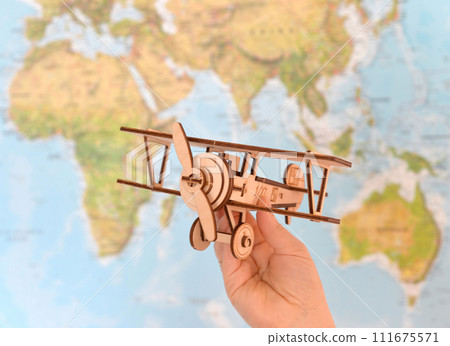 Travel and tourism concept. hand holding toy airplane against map of world Travel and tourism concept. hand holding toy airplane against map of world 111675571