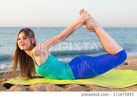 Smiling young woman in blue T-shirt is practicing stretching 111675845