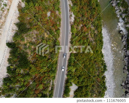 Aerial drone view of rocky canyon Moraca river with big stone boulders, asphalt road with moving cars, Montenegro. Vibrant lush green vegetation in summer. Popular travel destination Aerial drone view of rocky canyon Moraca river with big stone boulders, asphalt road with moving cars, Montenegro. Vibrant lush green vegetation in summer. Popular travel destination 111676005