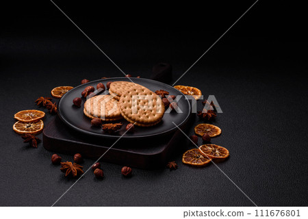 Round dotted snack snack cookies with cream on a dark concrete background Round dotted snack snack cookies with cream on a dark concrete background 111676801