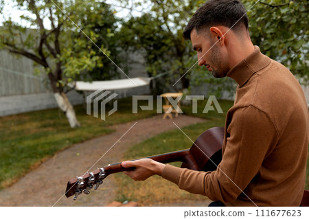young man sits at the table and plays the guitar 111677623