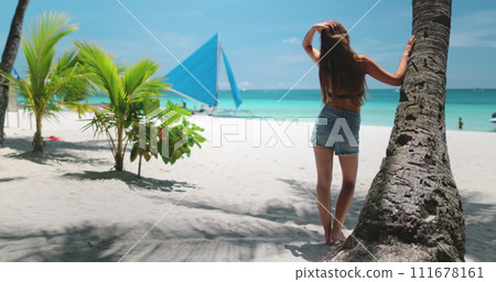 Woman relax on beach under coconut palm tree enjoy tropical island landscape. Boracay, Philippines. Yacht saining boats, turquoise water, blue sky. Outdoor lifestyle travel on summer holiday vacation 111678161