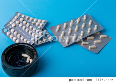 Medical background of many white capsule tablets or pills on blue table 111678276