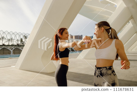 Sporty women non-contact greeting together outdoor meeting for fitness training or running outside Sporty women non-contact greeting together outdoor meeting for fitness training or running outside 111678631