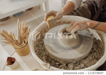 Close up of hands of professional potter molding pot shape on pottery wheel. Ceramics art concept  111678697