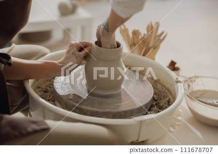 Close up of artisan's hands shaping clay bowl in pottery studio. Pottery art and creativity Close up of artisan's hands shaping clay bowl in pottery studio. Pottery art and creativity 111678707