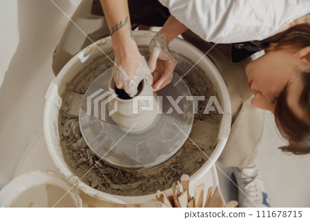 Close up of artisan's hands shaping clay bowl in pottery studio. Pottery art and creativity 111678715